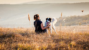 Woman sitting in a field with a dog 